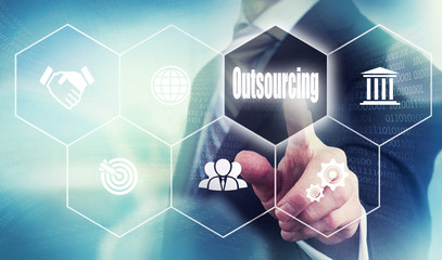 Businessman pushing a outsourcing concept button.