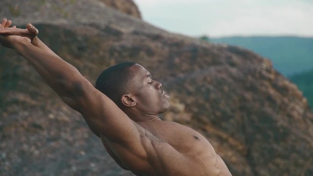 Close-up of african american bodybuilder with naked torso stretching outdoor