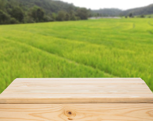 Wood table top with blur green rice fields background. use for m