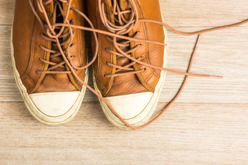 Old leather sneakers on wooden background top view, horizontal i