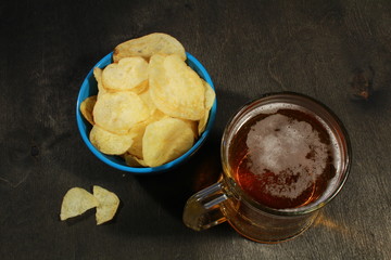Mug of beer with snacks on wooden table