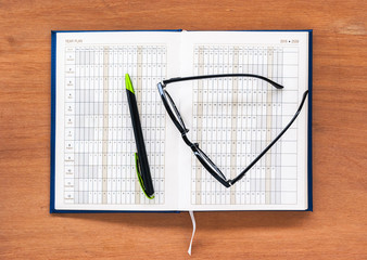 Diary planner book open calendar page with glasses and pen on th