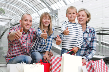 Family with shopping bags in the shopping center showing thumbs