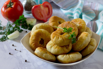 Open pies with meat (belyashi) and fresh vegetables on a gray st