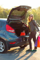 Woman putting her shopping bags into the car trunk