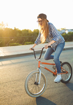 Lovely young woman in a hat riding a bicycle on city background