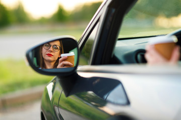Young woman with coffee to go driving her car