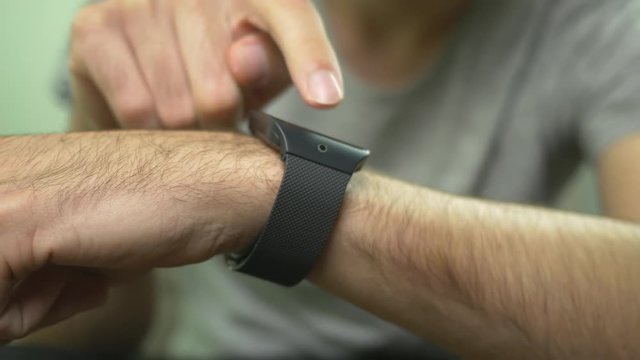 Young male using his smartwatch on his wrist.