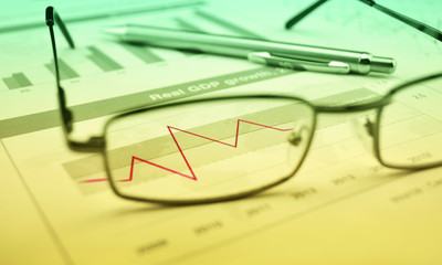 Glasses and pen on financial chart and graph, success concept, g