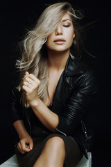 Naklejka premium very beautiful girl sitting on a chair in the studio in a leathe