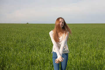 woman with open arms in the green wheat field at the morning