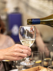 Pouring White Wine into a Glass Held by a Hand in Close Up