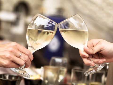 Two People Touching Glasses of White Wine Celebrating an Event 