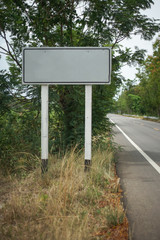 clear white road sign with a blank space for text, with a grass