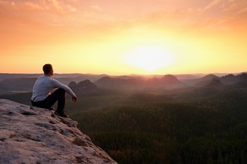 Tourist watching sunrise above  misty hilly valley