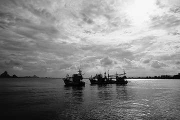 silhouette of three traditional boat laying on the sea with peace wave, black and white picture style
