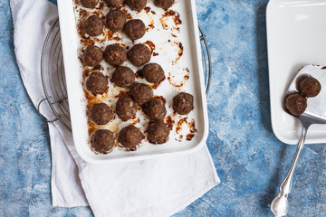 Baked Beef meatballs in white ceramic oven sheet. 