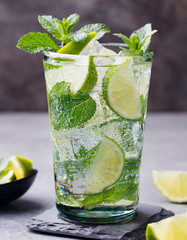 Mojito cocktail with lime and mint in highball glass on a grey stone background