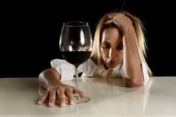 drunk alcoholic blond woman alone in wasted depressed drinking red wine glass suffering hangover