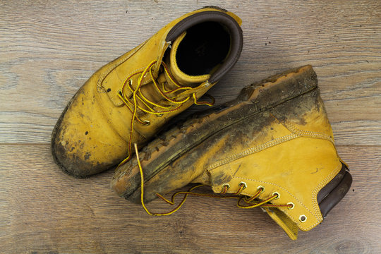 Muddy work boots on a wooden floor