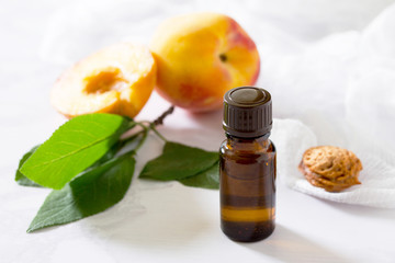 Cosmetic oil from the seeds of peach in a glass bottle on a gray