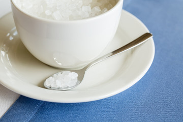 cup of refined sugar on the white- blue background