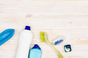 Cleaning items and tools lying on textured white floor background. Frame for cleaning concept or advertising. Empty copy space around products.