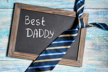 Fathers day concept, Best Daddy written on chalkboard with blue striped tie on wooden background