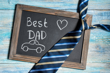 Fathers day concept, Best Dad written on chalkboard with blue striped tie on wooden background