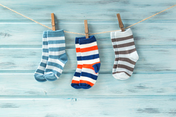 Baby striped socks on a clothesline on wooden background