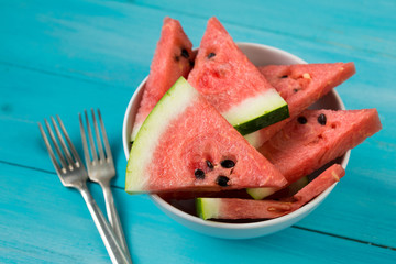 Slices of watermelon in a bowl, blue wooden background