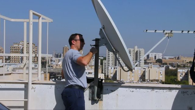Technician adjusting of a satellite television plate with satellite channels finder,