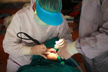 Dentist clean and polish a patients teeth in the dentists chair