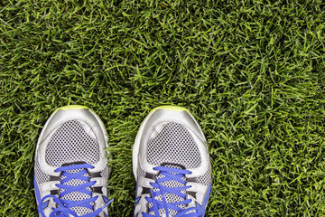 Silver running shoes on green grass.