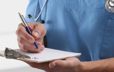 Male doctor writing prescription on clipboard