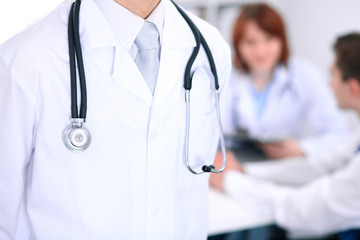 Close-up of a male doctor in a background of doctor and patient