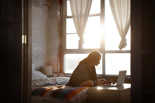 Young woman surfing net on bed
