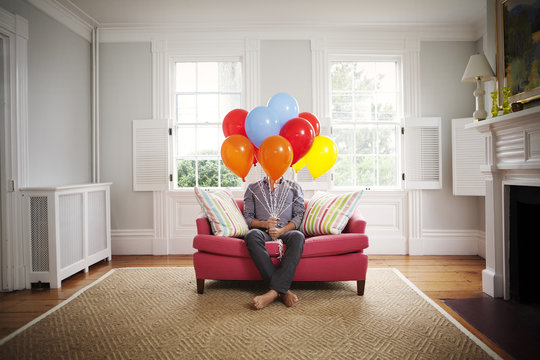 Man sitting on couch with balloons