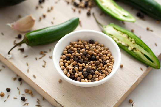 Black and white peppercorns  in bowl and green chili peppers