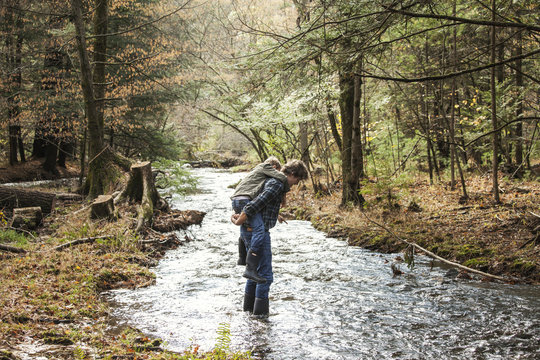 View of father with son (8-9) walking through stream