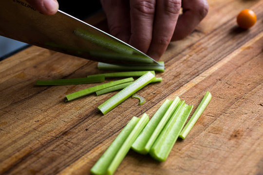 Person chopping celery on wooden chopping board