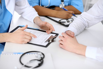 Two doctors and male patient discussing medical history at the table, close up