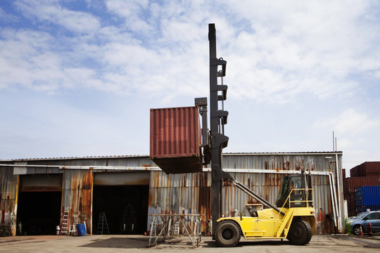 Crane lifting up container in warehouse