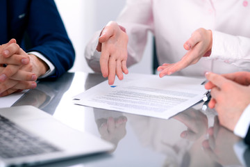 Group of business people and lawyers discussing contract papers sitting at the table, close up