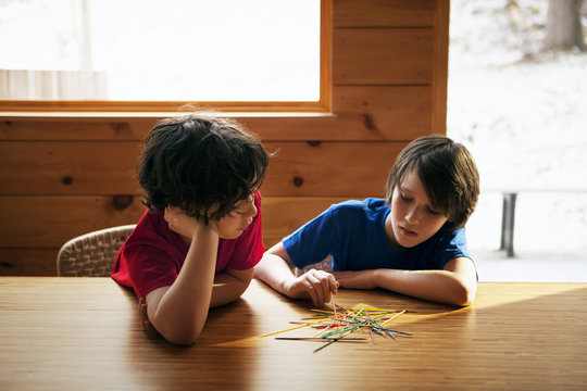 Brothers (8-9,  10-11) playing pick up sticks