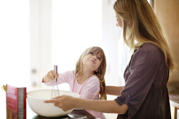 Girl (4-5) making pancakes with mother