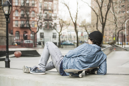 Young man leaning on skateboard,