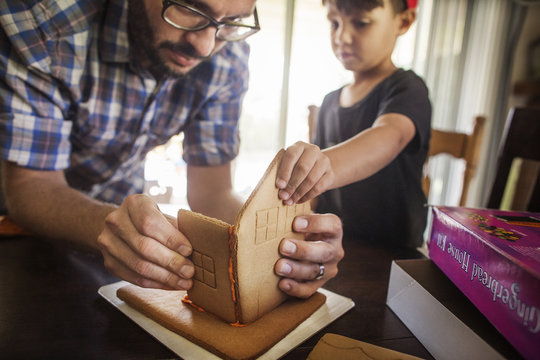 Father with son (4-5) building cookie house