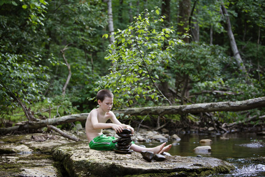 Boy playing with stones by river