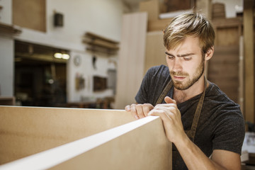 Man working on wooden plank in carpentry workshop